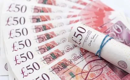 a roll of £50 notes on top of a fan of money
